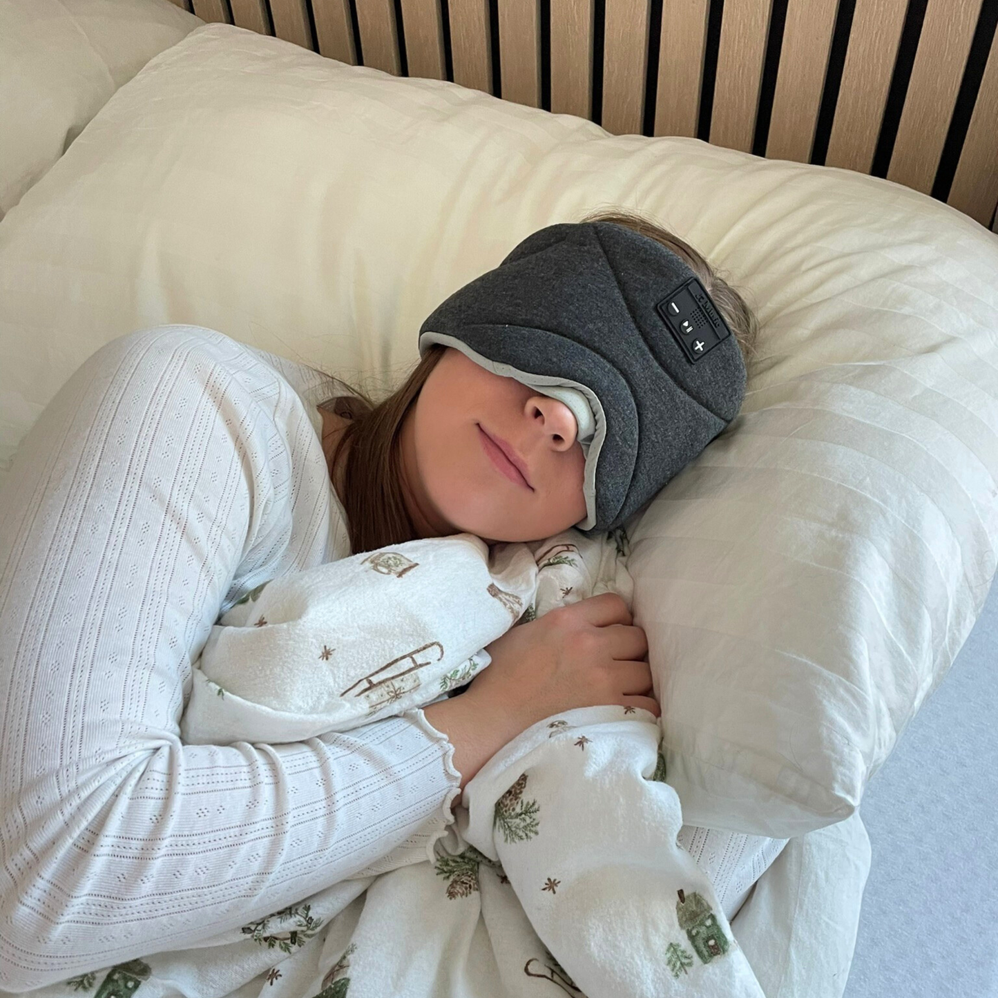 Ung kvinne som hviler i sengen med Dreamli sovemaske – trådløs maske for dyp og behagelig søvn.